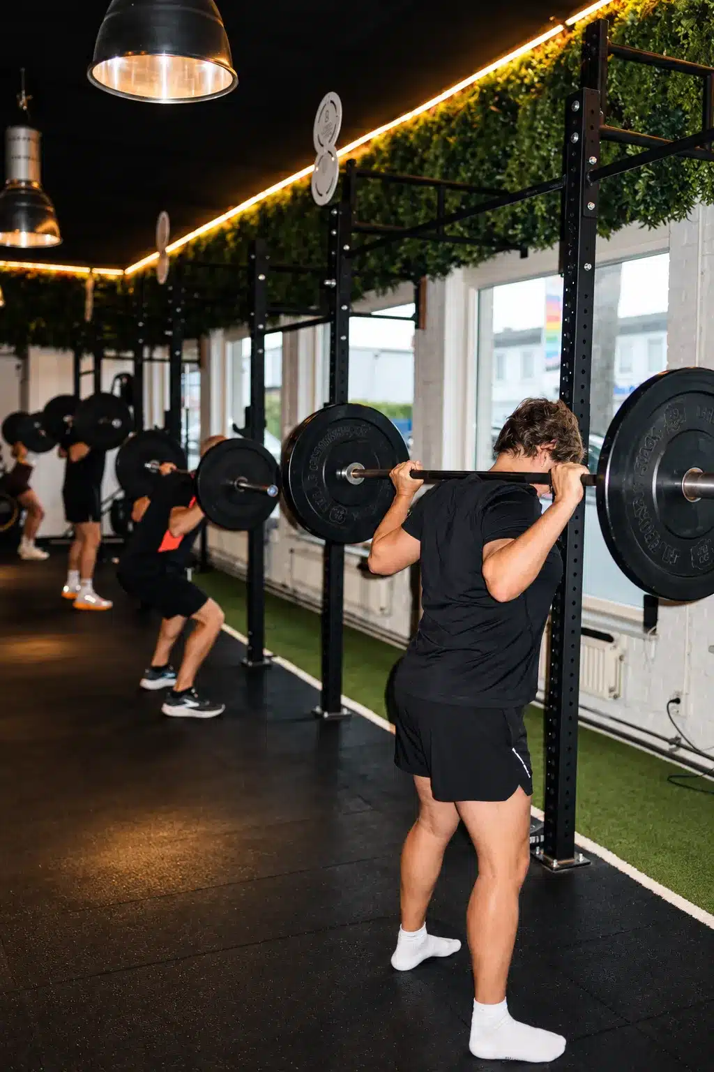 Deelnemer doet een barbell squat tijdens een training bij Modern Trained