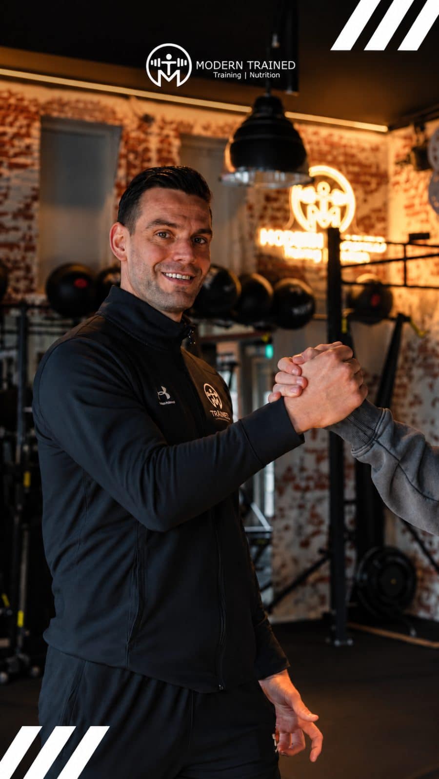 Xander Smolders van Modern Trained geeft een klant een hand in de gym